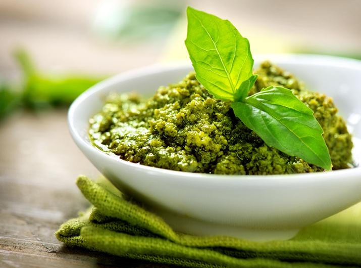 Fresh basil pesto in a white bowl.