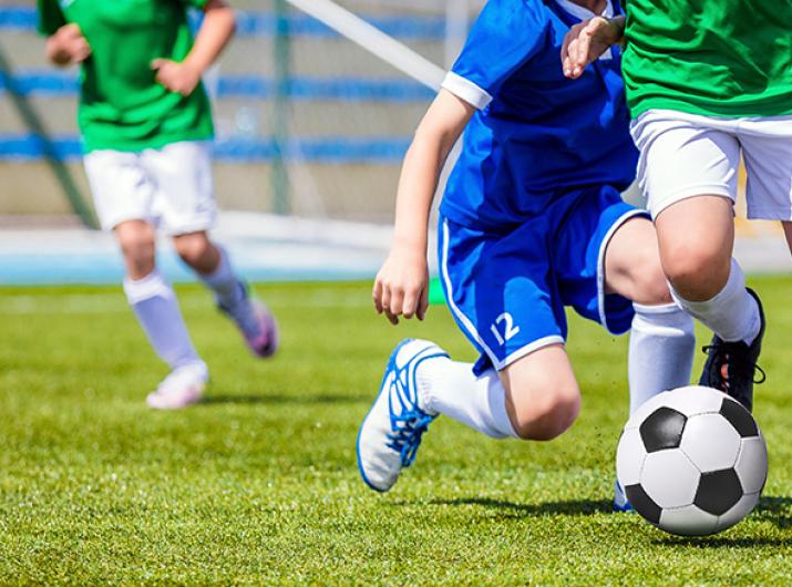 Children playing soccer on a green field.