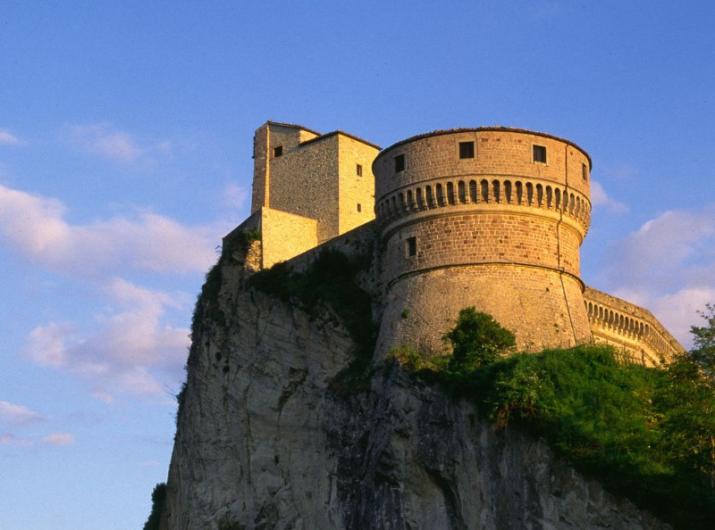 Castelo em um penhasco ao pôr do sol, imponente e histórico.