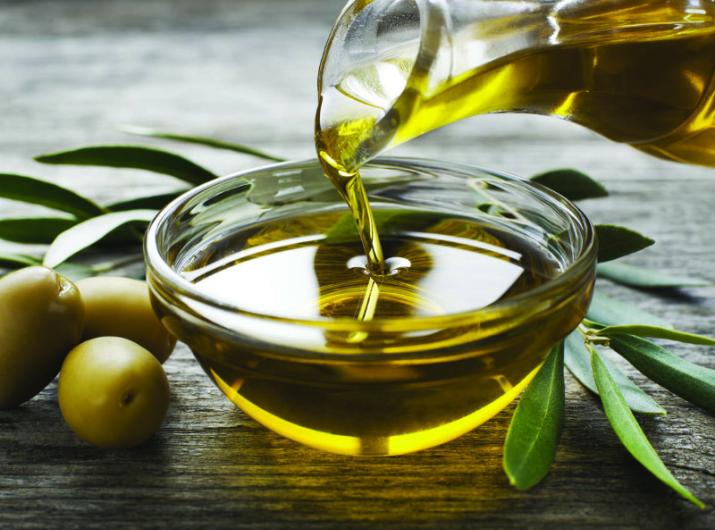 Olive oil poured into bowl with olives.